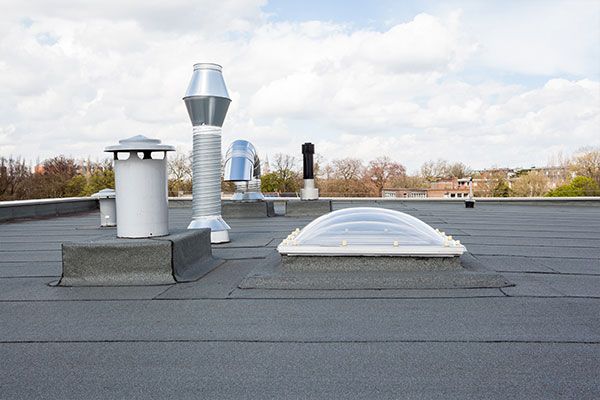 A flat roof with a skylight and some pipes.